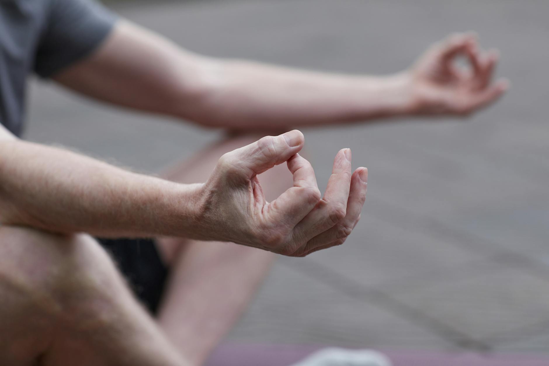 Close-up of hands in a meditation pose outdoors, symbolizing peace and mindfulness.