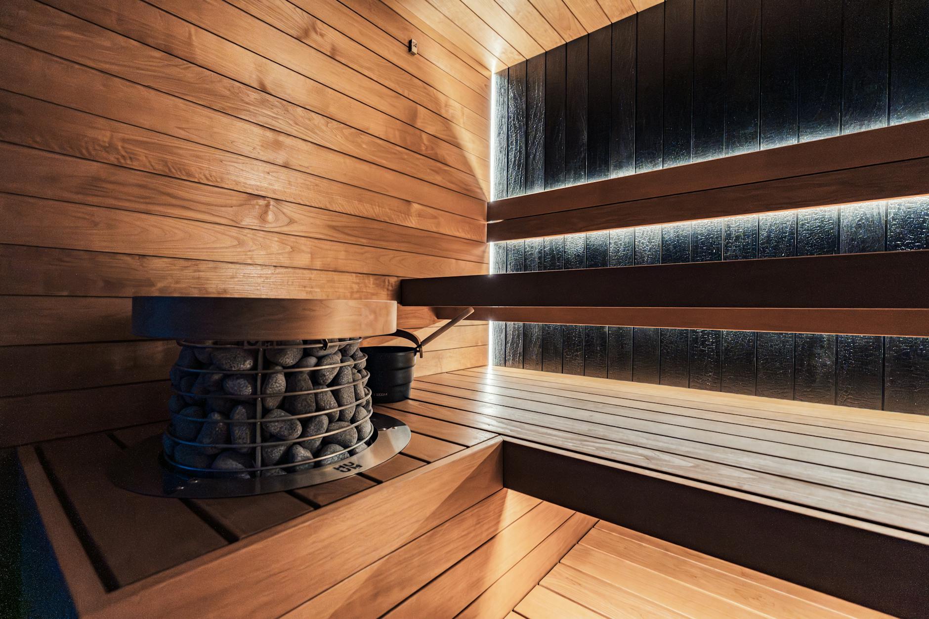 A stylish and modern indoor sauna with a premium heater and wooden panels, offers a relaxing wellness retreat.