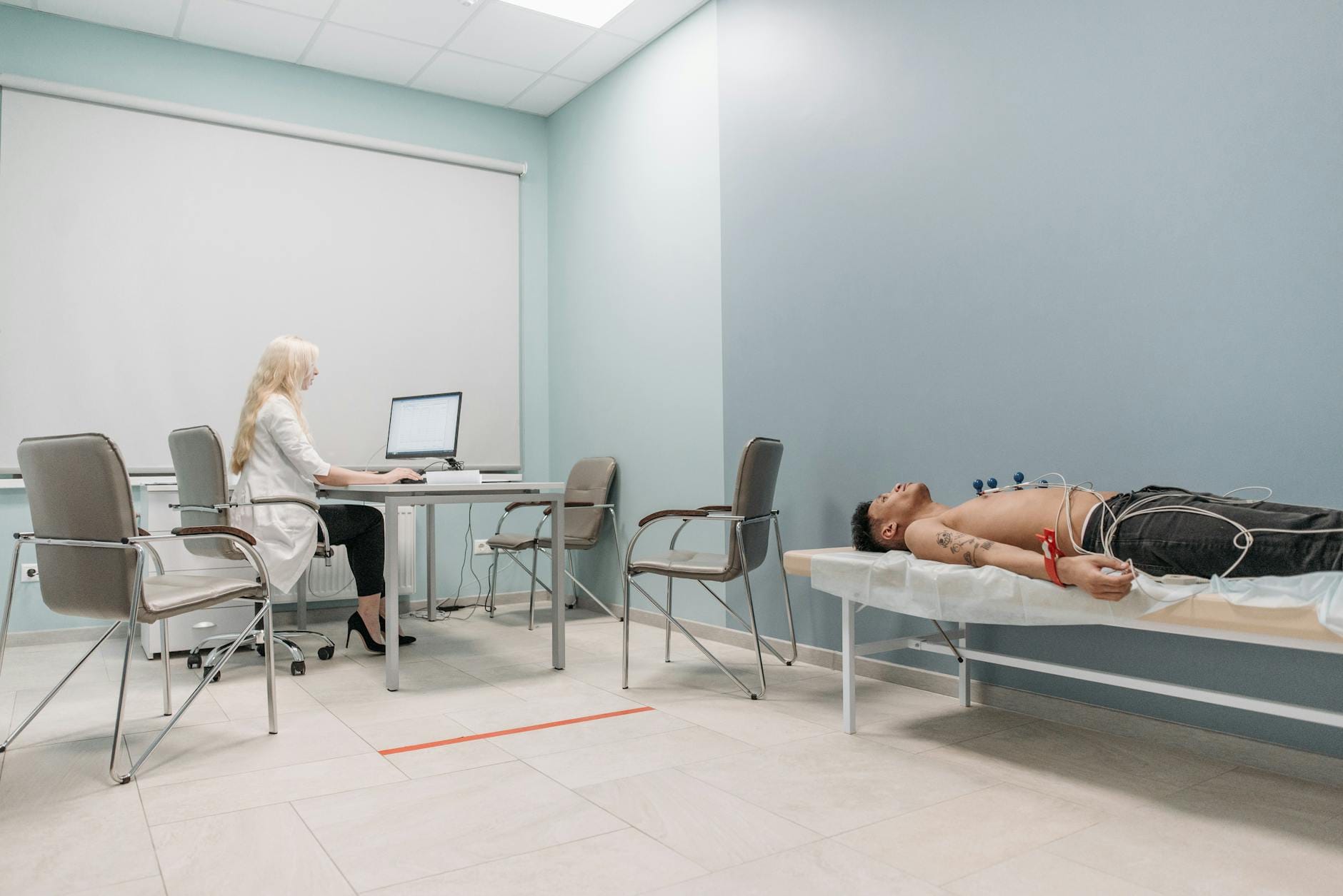 A medical professional monitors a man undergoing ECG procedure in a clinical setting.