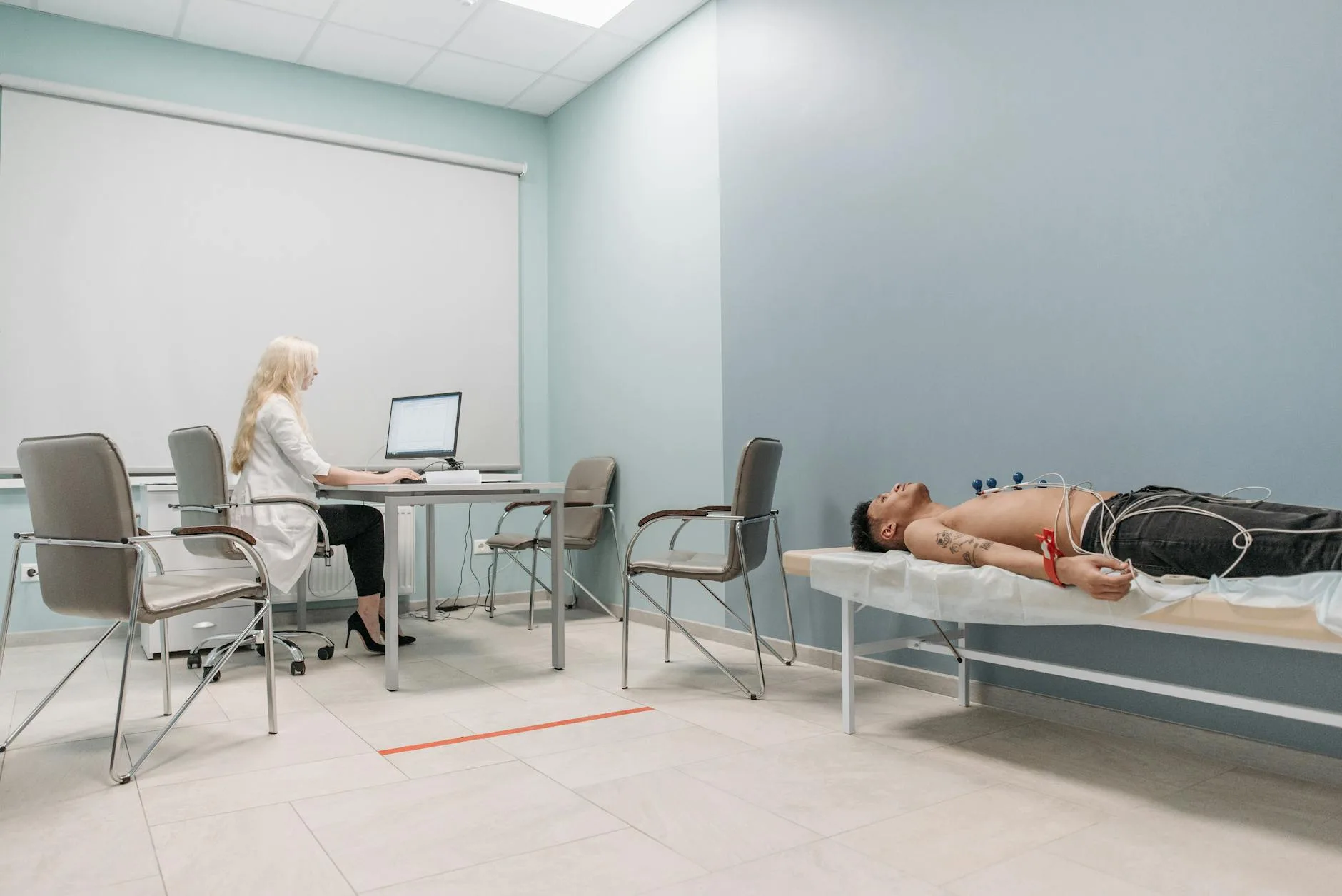 A medical professional monitors a man undergoing ECG procedure in a clinical setting.