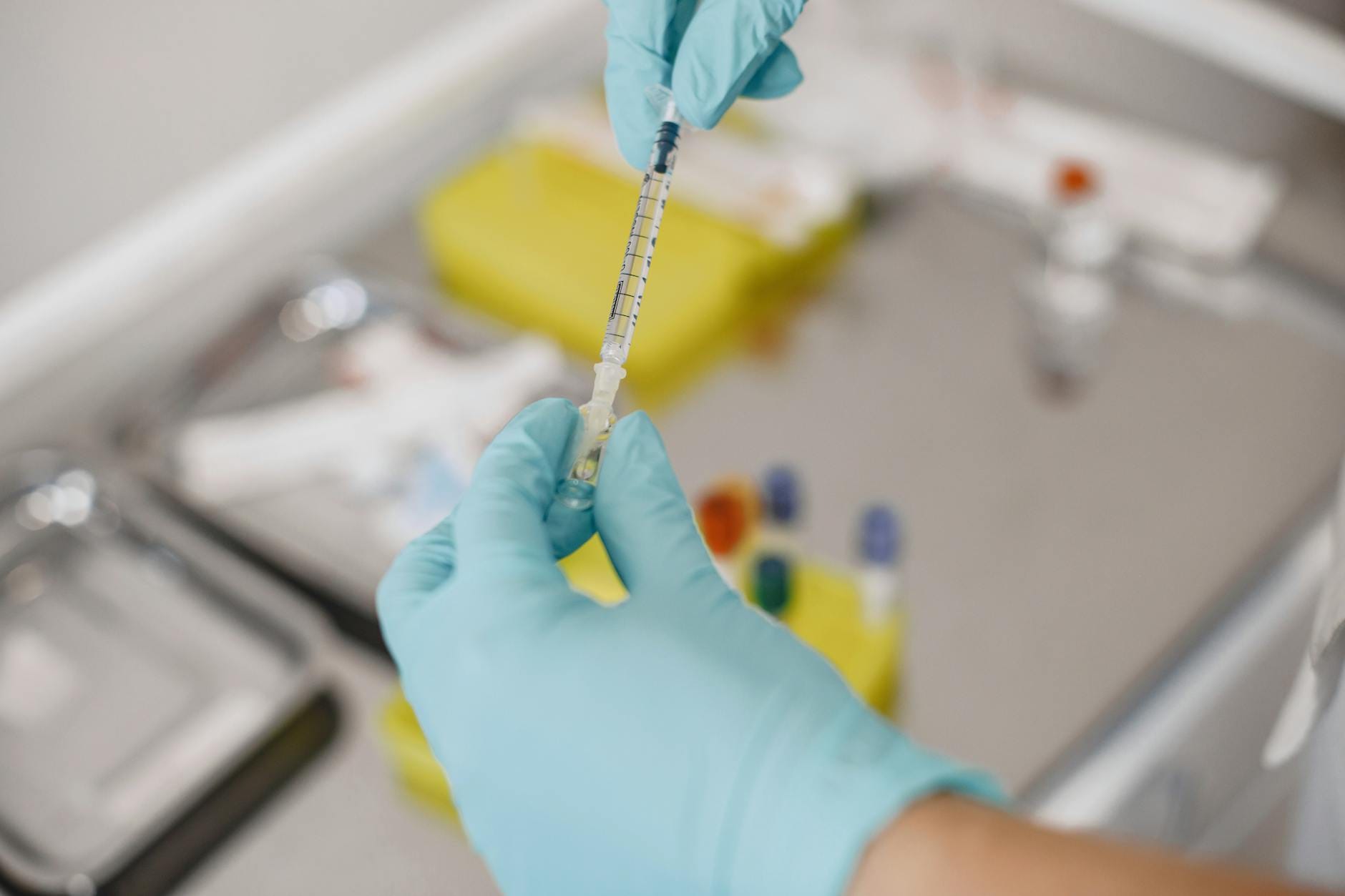 A close-up of gloved hands preparing a syringe in a medical lab setting, emphasizing hygiene and precision.